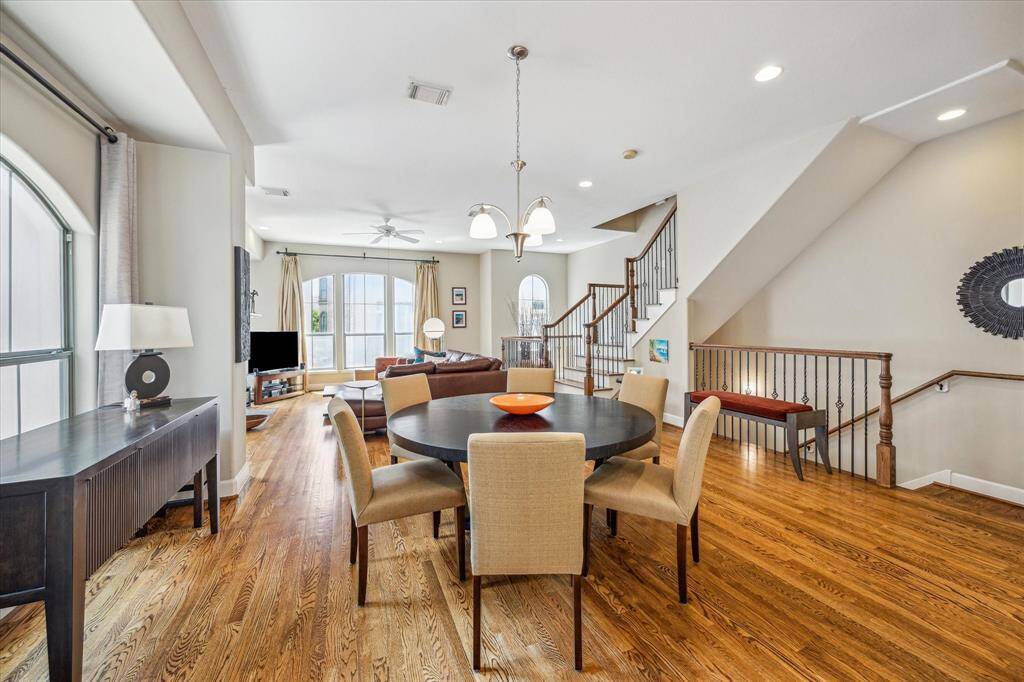 The second-floor living area welcomes you with rich hardwood floors, abundant natural light streaming through arched windows, and a flowing layout that connects the dining room, seating area, and adjacent spaces for effortless everyday living and entertaining.