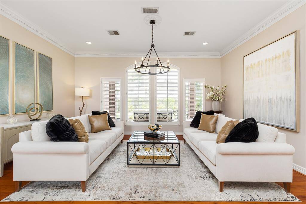 The Formal Living Room boasts a wall of windows looking into the back yard, dentil molding, beautiful wood floors, and updated lighting