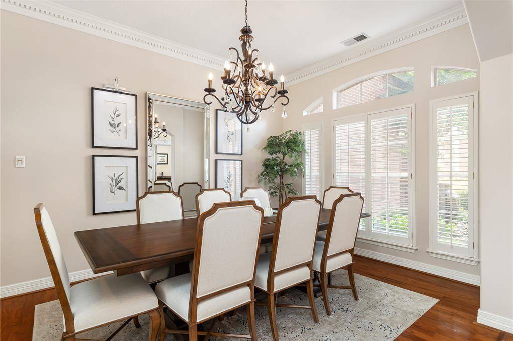The Formal Dining Room is situated at the front of the home, with 10" dentil crown molding, a beautiful chandelier, and shuttered windows for natural light.