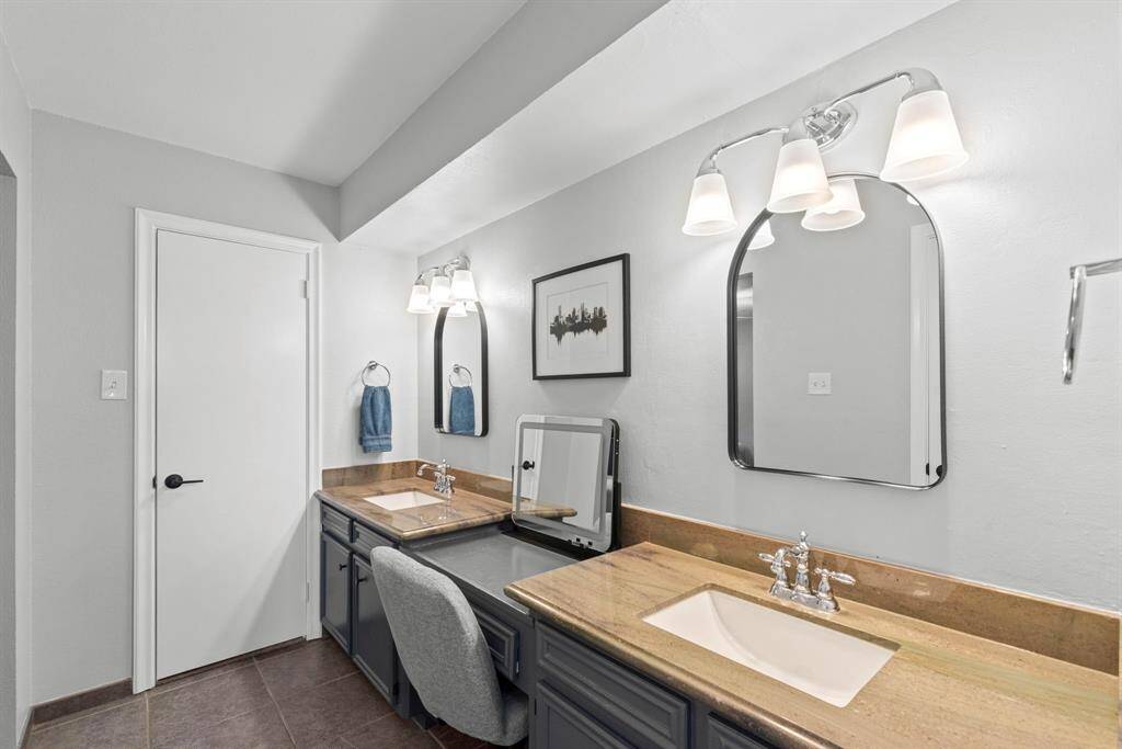 The primary bathroom features a double vanity with stylish mirrors and modern lighting. The neutral palette and ample counter space provide a clean, inviting atmosphere.
