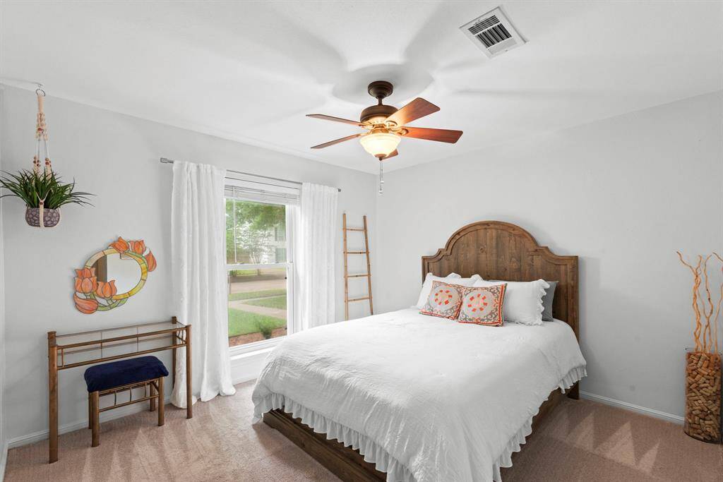 This bright bedroom features a ceiling fan and a large window offering a pleasant view and natural light.