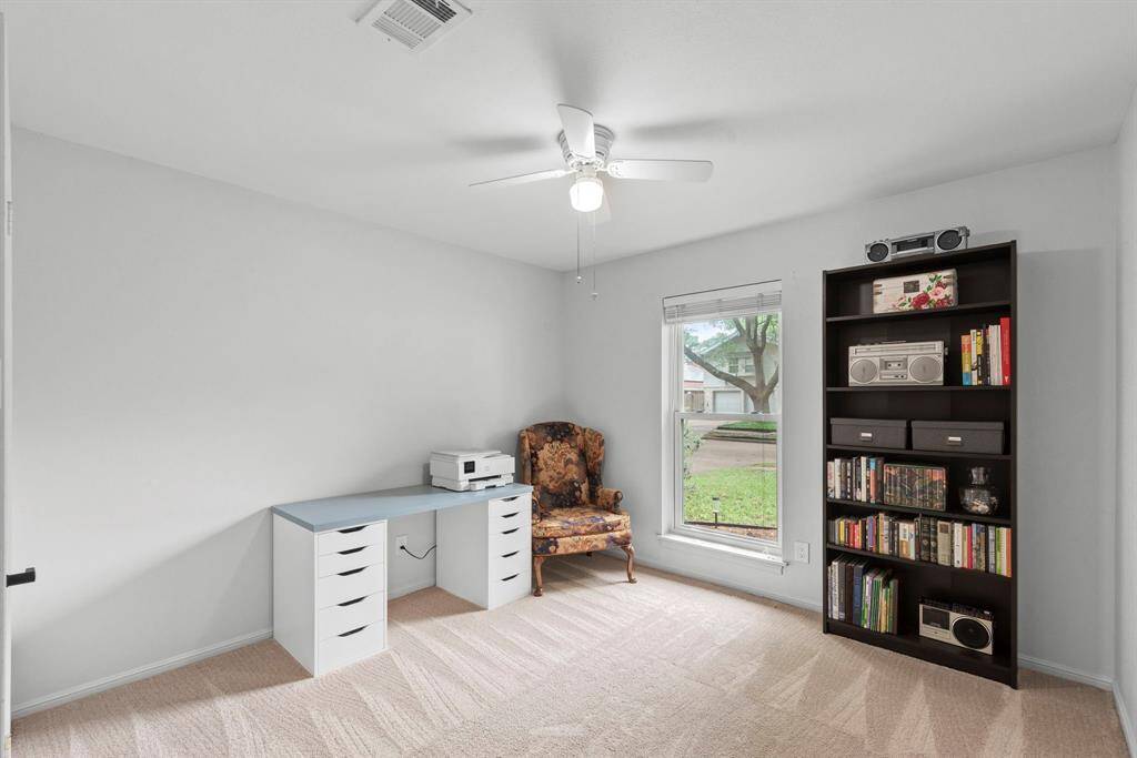This room features a large window for natural light, neutral walls, and carpet for a versatile space.