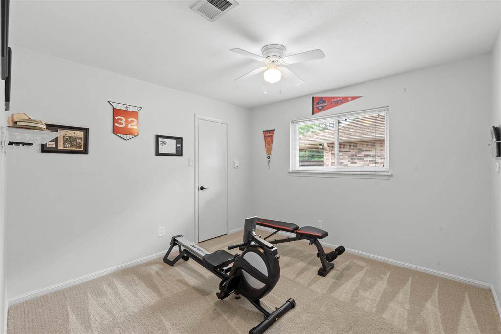 This room features neutral walls and carpet, with a ceiling fan and a window providing natural light.