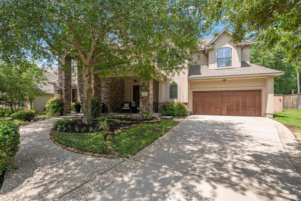 Two-story Leigh Custom home just steps away from the Gary Player course. A spacious driveway leads to a two-car garage, surrounded by mature trees, offering both beauty and privacy.