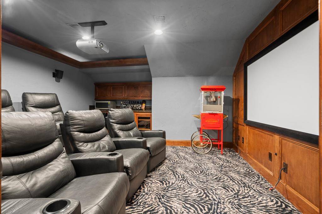 The home theater features comfortable leather recliners, a large screen, and  a ceiling-mounted projector, creating a perfect entertainment space.