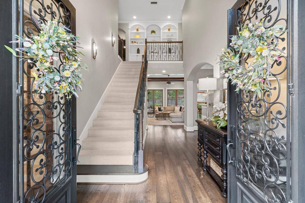 This elegant home featuring a grand entrance with decorative iron doors. Inside, you'll find a spacious foyer with a staircase, high ceilings, and abundant natural light.
