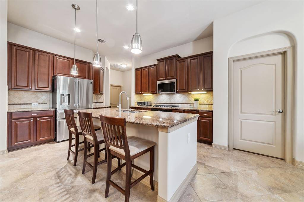 Spacious kitchen with ample wood cabinetry, a large island with breakfast bar, granite countertops, and a walk-in pantry. Newly updated oven, microwave, and dishwasher in 2024.