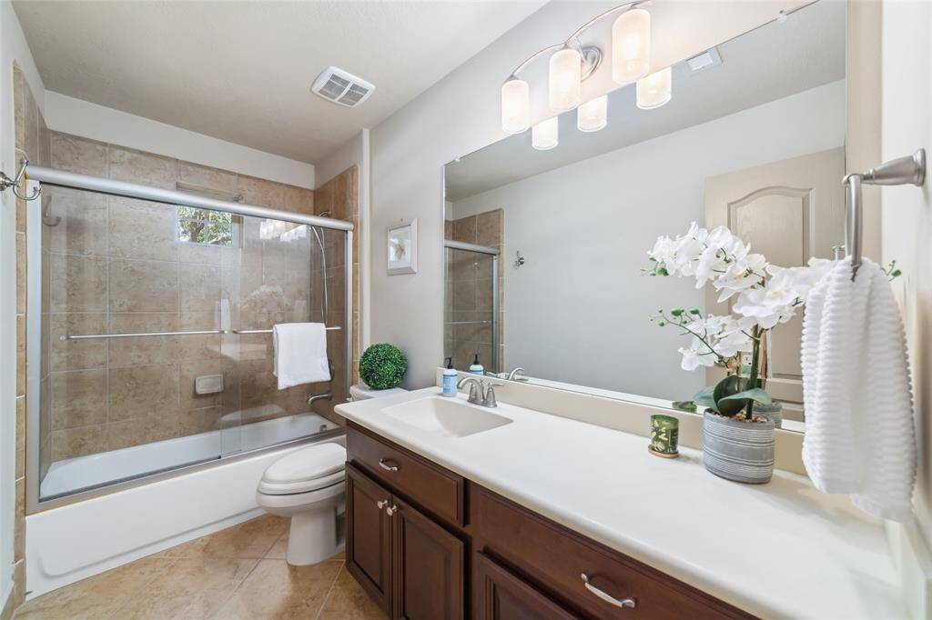 Stylish secondary bathroom featuring a sleek glass-enclosed tub and shower combo.