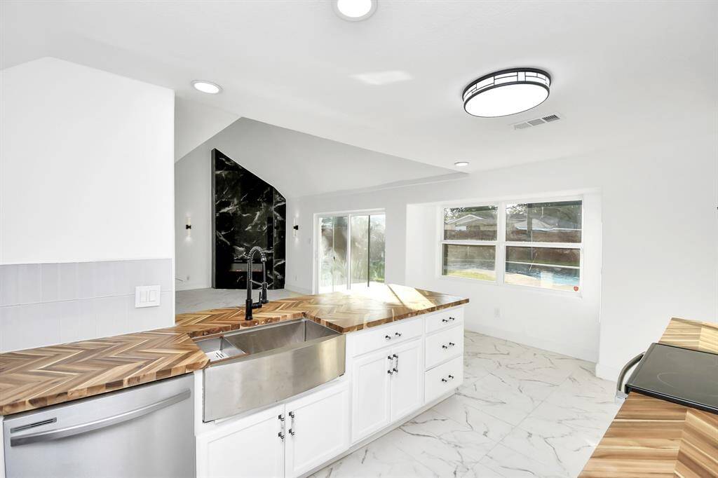 The kitchen features top-of-the-line stainless steel appliances, highlighted by a custom stainless farmhouse sink.