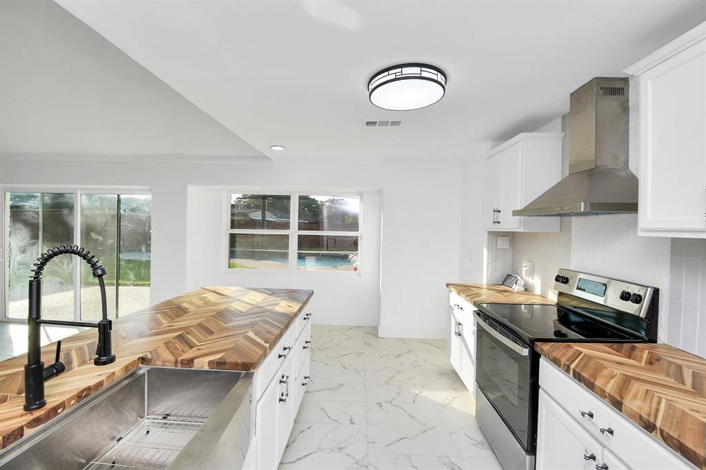 The herringbone butcher block countertops stand out in this kitchen, creating a striking and eye-catching focal point.