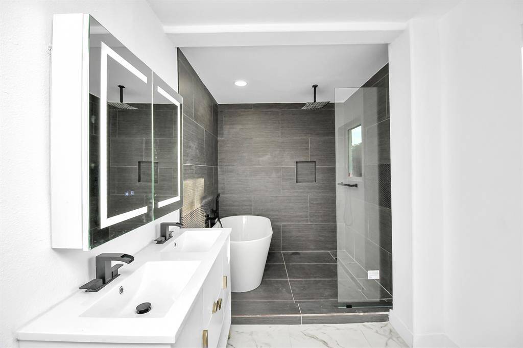 The downstairs bathroom offers every luxury, featuring touch screen smart mirrors, a seamless glass shower, and a freestanding soaking tub, leaving nothing to be desired.