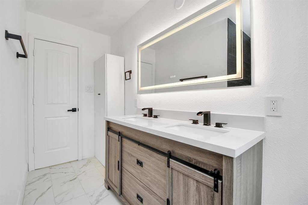 Another updated bathroom upstairs features a smart mirror and dual sinks.