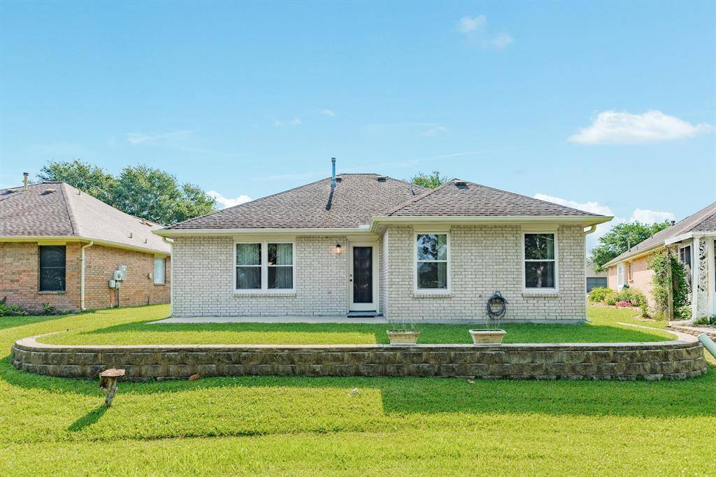 Raised back yard with brick wall and large patio.