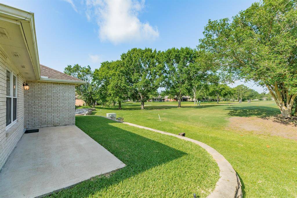Raised back yard with brick wall and large patio, with golf course view.