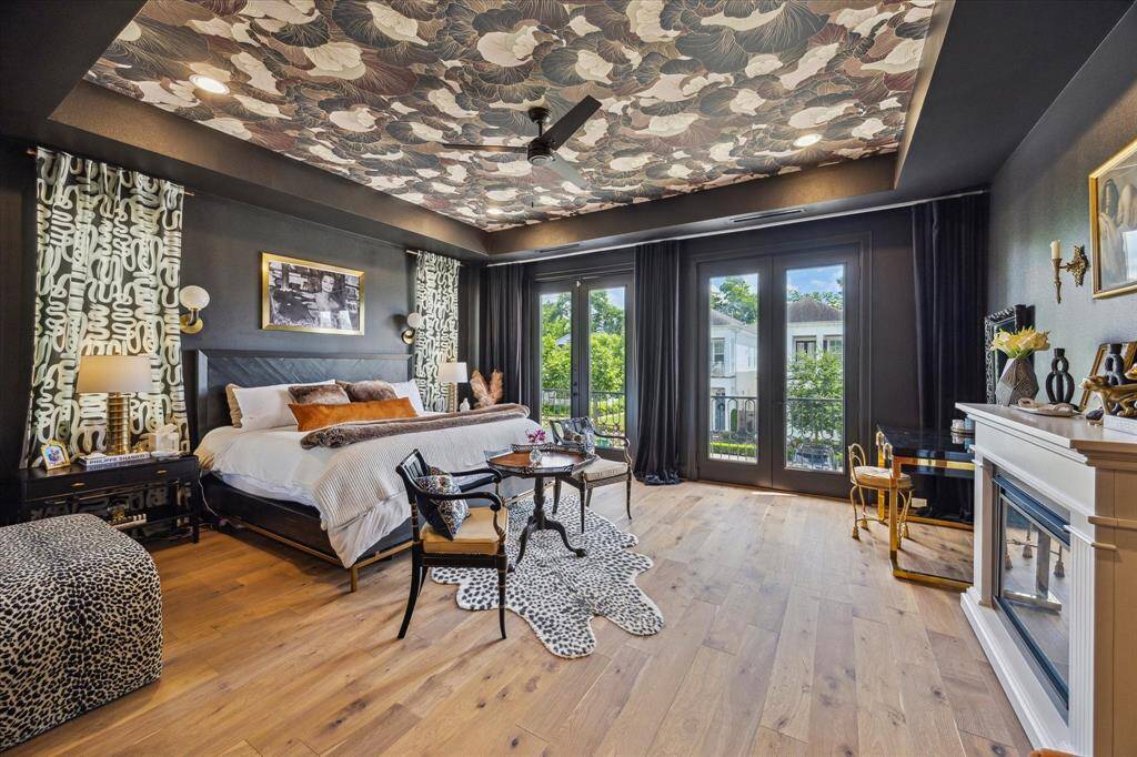 Spacious bedroom features elegant design elements and large doors leading to juliet balcony. The room is tastefully decorated with a cozy sitting area, fireplace and stylish drapery