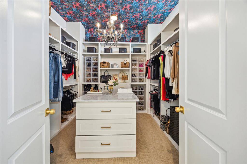 Spacious walk-in closet featuring ample shelving and hanging space, a central island with drawers and plenty of storage