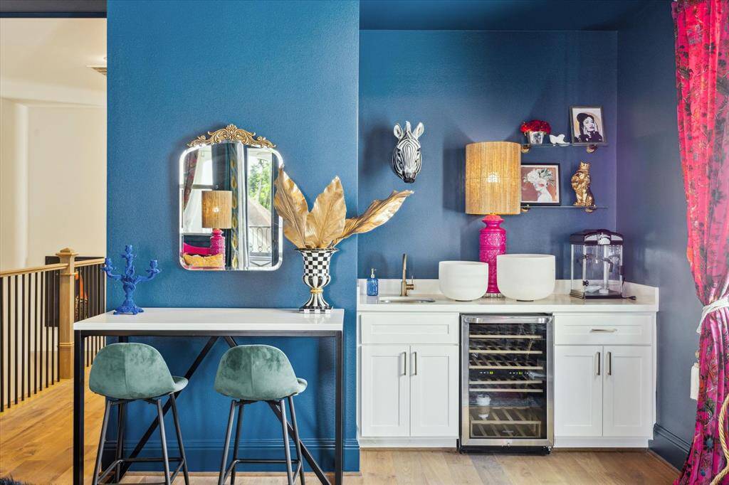 This space features a stylish blue accent wall with wet bar area, complete with a wine fridge and sink.