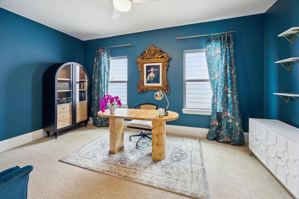 Home office/flex space is well-lit with natural light from two windows adorned with floral curtains, creating a sophisticated atmosphere.