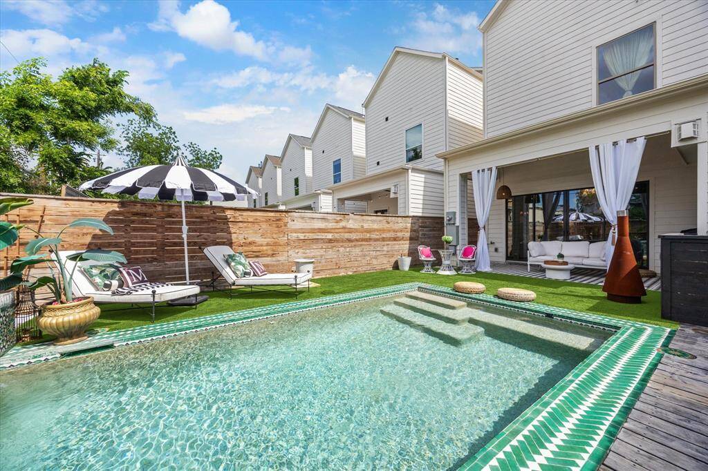This backyard features a gorgeous rectangular pool with custom morroccan tile edging, surrounded by turf and decking. Perfect for relaxation and entertainment.