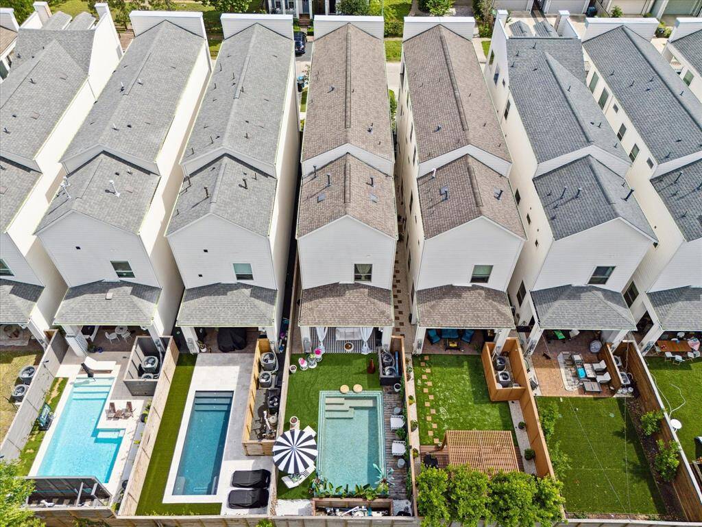 This aerial view showcases private large fenced backyard with pool, turf and multiple seating areas