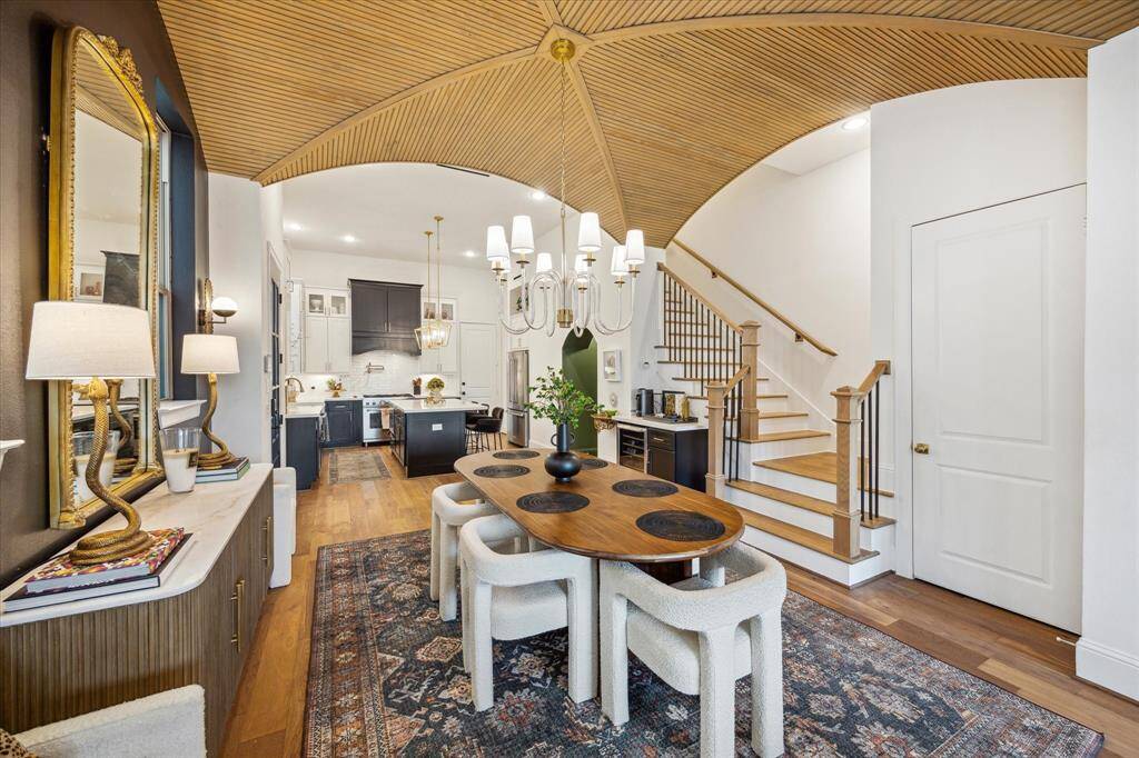 A beautifully curved staircase adds character, while the kitchen includes sleek cabinetry and an island. The area is well-lit and invites a warm, welcoming atmosphere.
