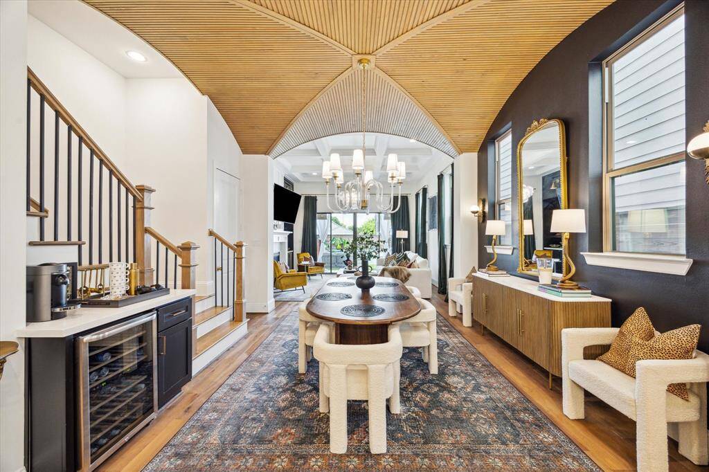 Elegant living space features a vaulted ceiling, stylish dining area with a large table and plush chairs and wine fridge