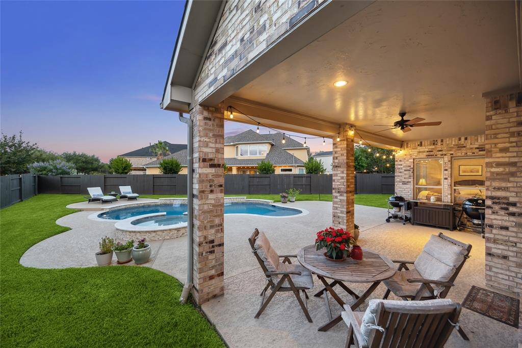 Sparkling pool paired with a covered patio featuring a ceiling fan, creating a refreshing outdoor retreat perfect for relaxing, entertaining, or escaping the Texas heat in comfort and style.