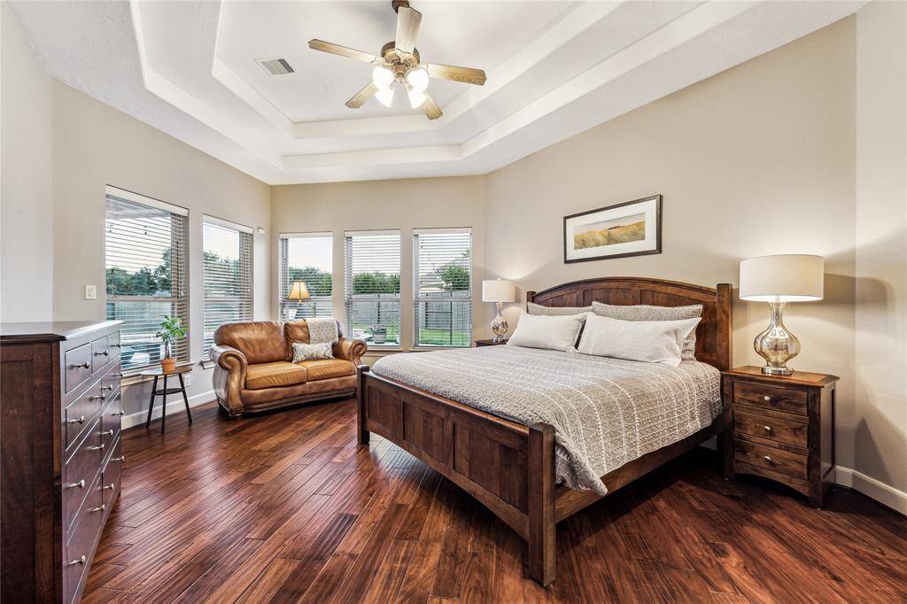 Spacious primary bedroom with a step-up ceiling and an abundance of windows offering beautiful views of the backyard oasis.