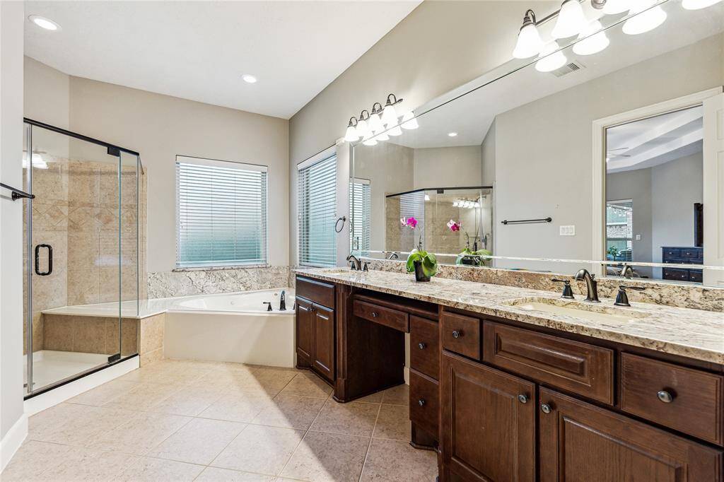 En suite bath featuring dual vanities, a relaxing soaking tub, and a sleek glass shower—creating a spa-like experience with ample space.