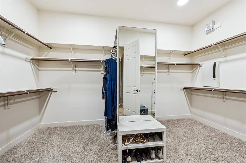 Spacious walk-in closet with ample room for both up and down hanging, full-length mirrors, and plenty of storage.