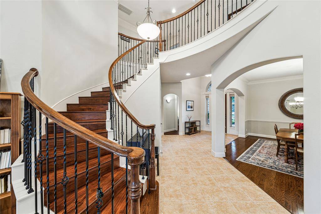 Elegant front entry showcasing a grand curved staircase with wrought iron railings.