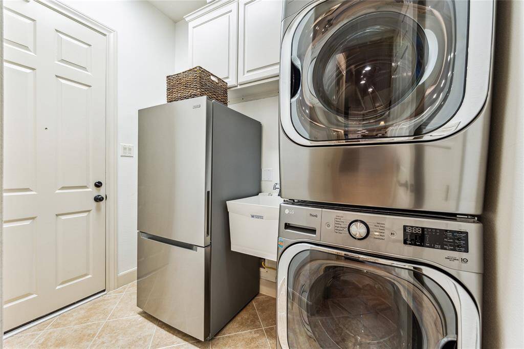 Spacious laundry room with ample storage, a convenient sink, and room for an additional refrigerator.