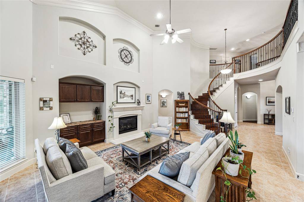 Inviting family room with soaring ceilings, a dramatic curved staircase, and an open flow into the island kitchen.