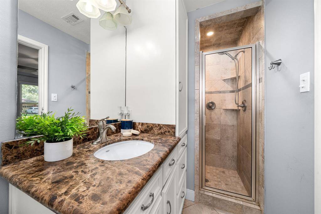 The primary bath features a beautifully tiled walk-in shower, granite vanity, and modern fixtures—your private space to refresh and relax.