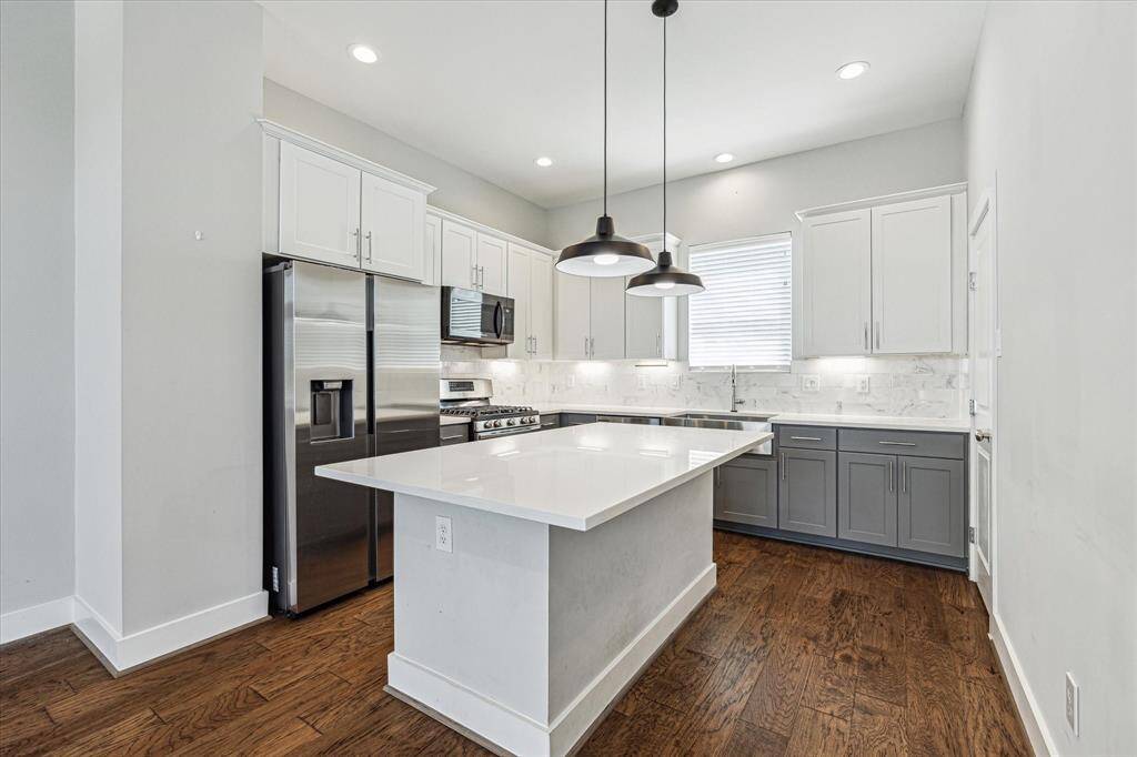 The kitchen offers island seating, two tone cabinets, a pantry, and plenty of storage and counter space.