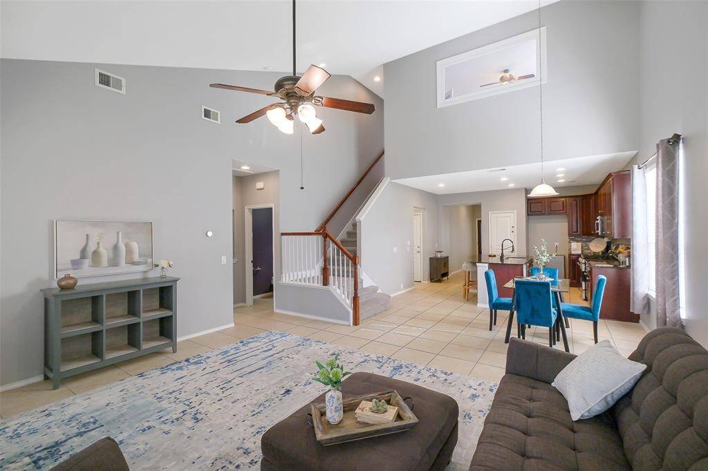 A great view of the downstairs living area, stairs, and the upstairs game room/office.