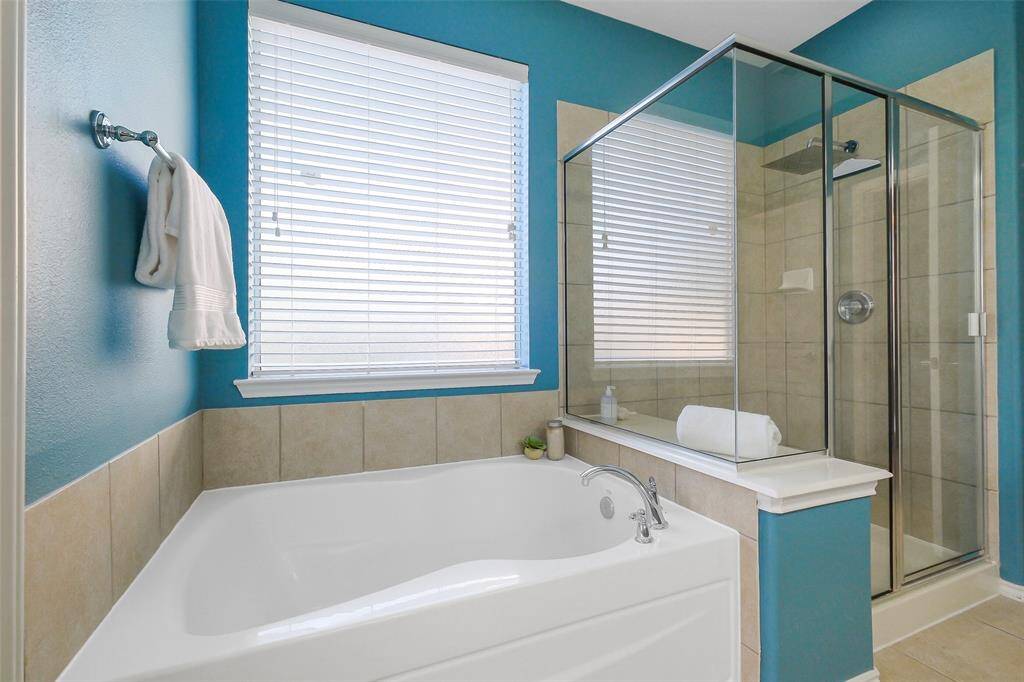 The oversized shower features a square rain shower head and shelf and the large soaking tub is ready for your relaxation.