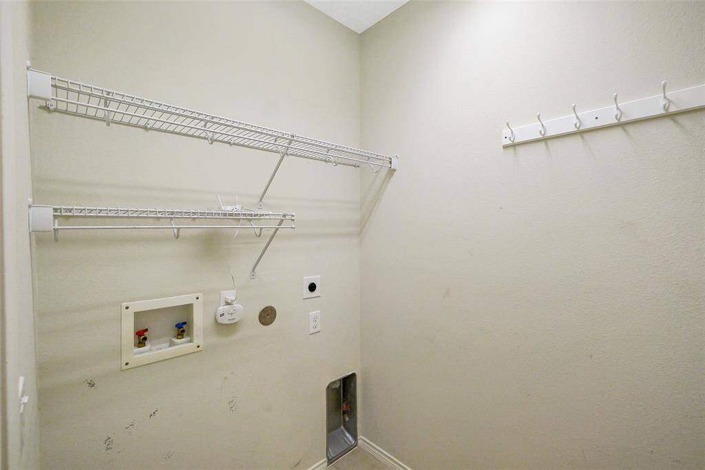 Laundry room is located off the kitchen and features open shelving.