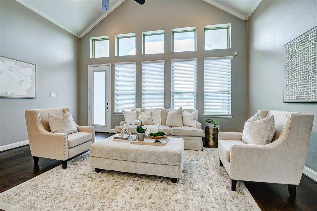 This living room features high ceilings and abundant natural light from large windows, creating a welcoming and sophisticated atmosphere.