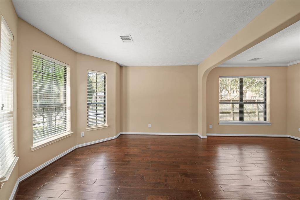 Additional view of the Family Room complete with handsome hardwood flooring, arched windows adding natural lighting, and an open concept allowing for ease of conversation from one area to the next