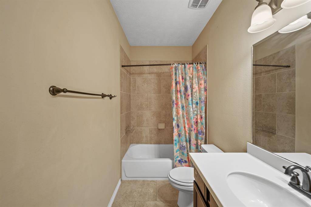 Full Bathroom with tile flooring, tub/shower with tile surround and counter with extended mirror