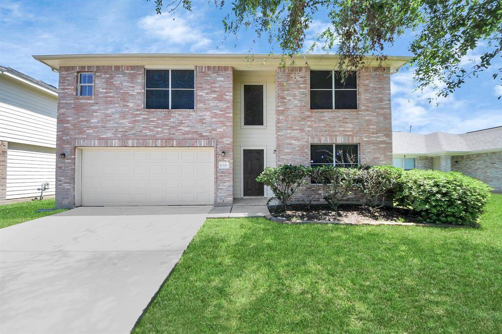 This is a two-story brick home with a two-car garage. It features a well-maintained front lawn, manicured shrubs, and a welcoming entrance. The windows are large, allowing for plenty of natural light.