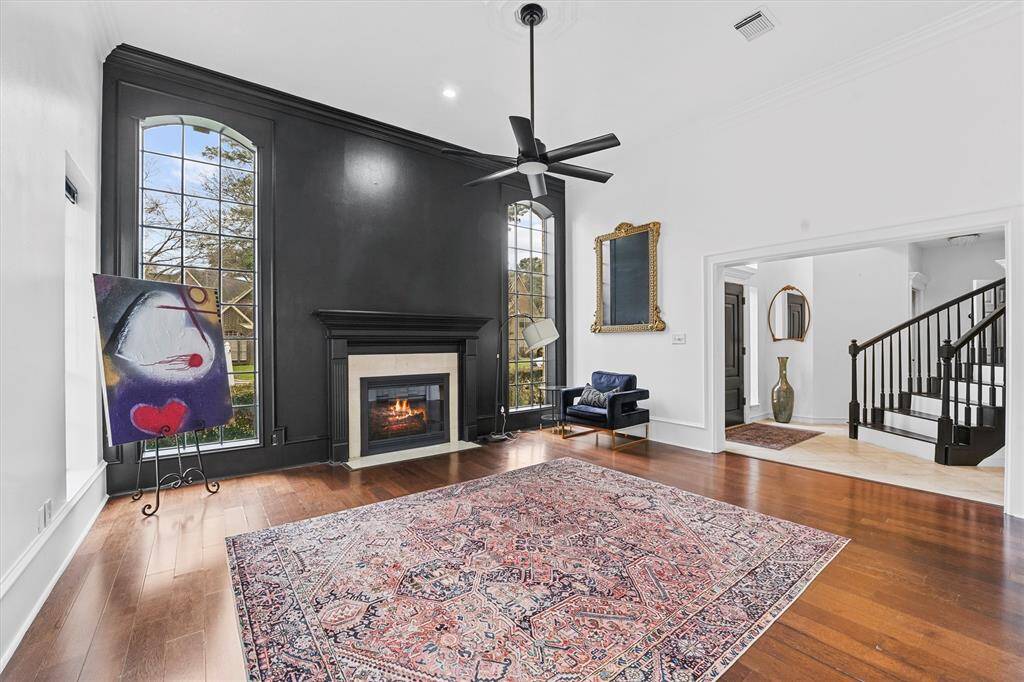 A dramatic black fireplace and soaring arched windows anchor this light-filled living room with timeless charm.