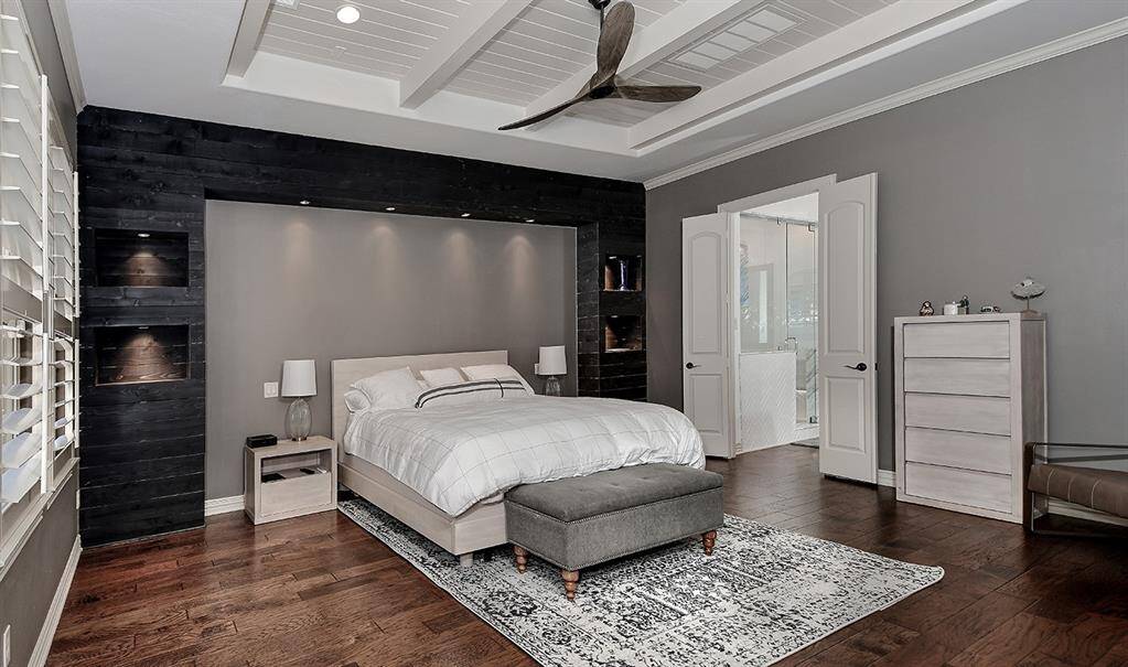 Main level primary retreat with custom shelves and accent wall treatment and accent lighting
