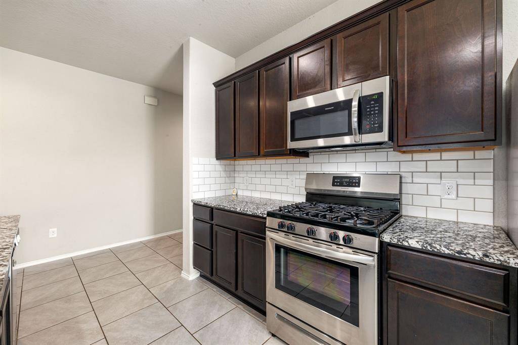 This stunning kitchen displays such a beautiful contrast with the dark stained cabinets, neutral paint, granite countertops, modern backsplash, SS appliances, oversized kitchen island with extra storage, breakfast bar and recessed lighting.