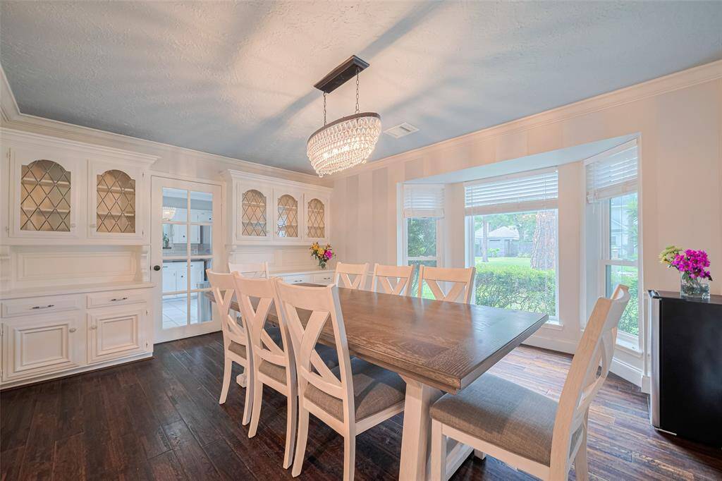 The formal dining room features built-in cabinets with glass fronts, and a glass panel door that provides access to the kitchen.
