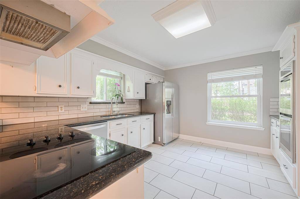 The spacious kitchen features elegant granite countertops, a stove, and a stylish backsplash, all updated in 2022.