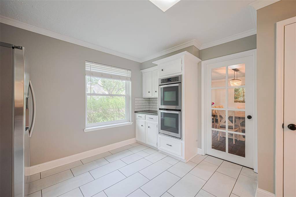 Another view of the kitchen highlights the double ovens, with a glass panel door providing access to the formal dining room.