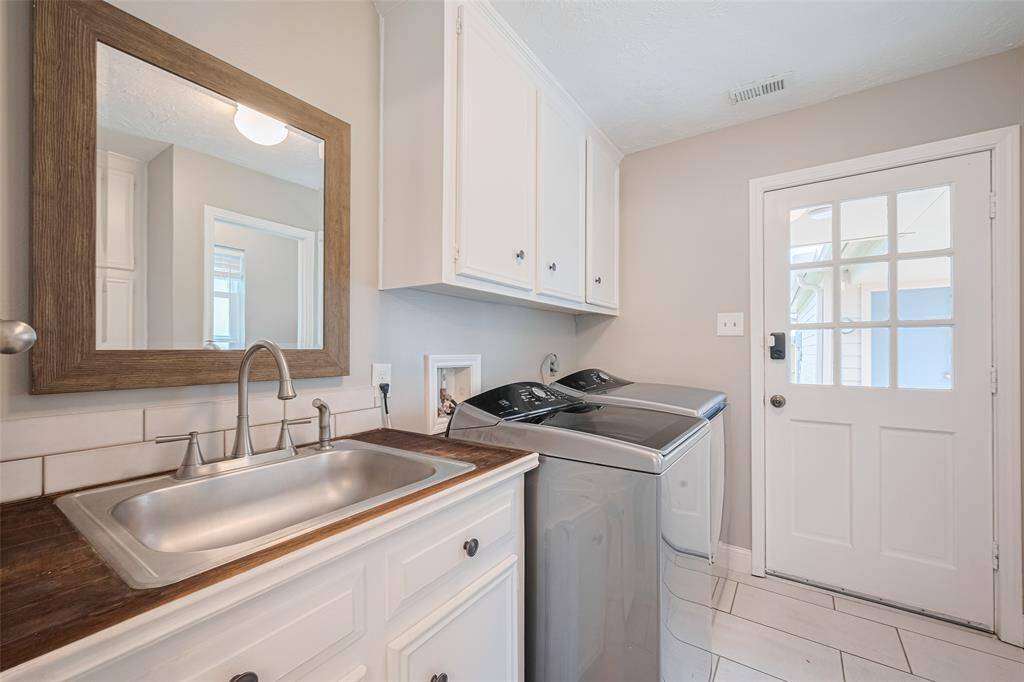 The utility room features a sink, with an adjacent half bath and access to a spacious yard and side courtyard.