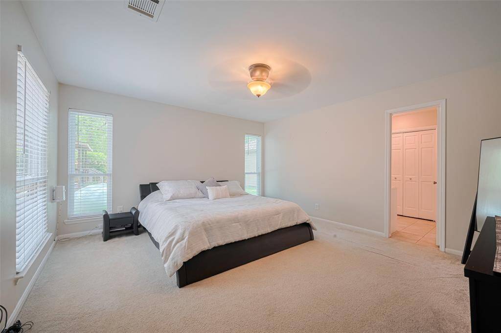 Spacious primary bedroom located on the first floor, featuring a door that leads to the primary bathroom and a lovely view of the backyard.